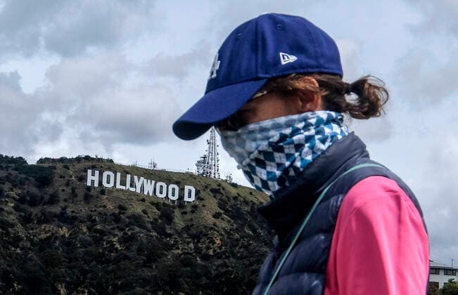 March 20, 2020, Los Angeles, California, U.S: A woman wearing a face mask walks by the Hollywood Sign on Friday. California Gov. Gavin Newsom issued a statewide stay-at-home order Thursday for residents to venture outside only for essential jobs, errands and some exercise, due to coronavirus concerns. Los Angeles USA - ZUMAc68_ 20200320_zaf_c68_002 Copyright: xRingoxChiux