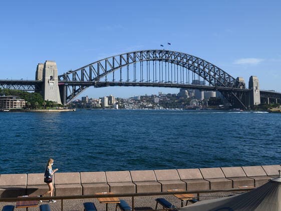 CORONAVIRUS AUSTRALIA, A lone woman wearing a protective face mask walks through a quiet Opera Bar in front of the Sydney Harbour Bridge, Sydney, Saturday, March 21, 2020. Sydney is seeing a dramatic reduction in people on the streets as people are asked to enact social distancing and self isolation in order to prevent the spread of Covid-19. ( NO ARCHIVING, EDITORIAL USE ONLY, NO USE IN BOOKS WITHOUT CONSENT SYDNEY NSW AUSTRALIA  Copyright: xJAMESxGOURLEYx 20200321001458535723
