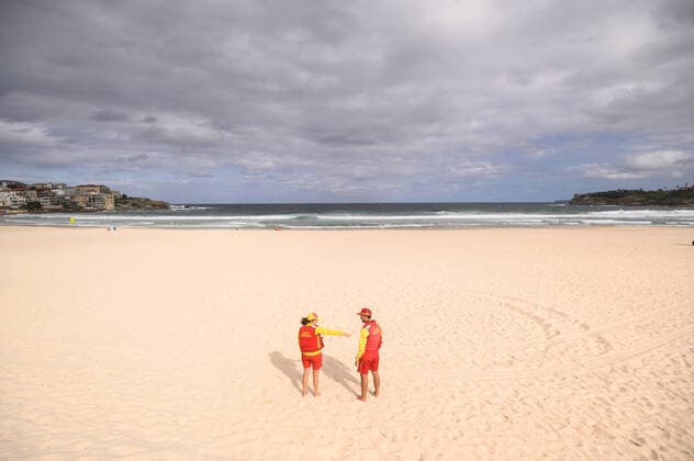 BONDI BEACH CORONAVIRUS CLOSURE, Surf life savers maintain a safe distance apart on an empty Bondi Beach following its closure this afternoon in Sydney, Saturday, March 21, 2020. Beachgoers drew condemnation yesterday when tens of thousands of people flouted social distancing rules, which have been put in place in an effort to limit the spread of COVID-19. ( NO ARCHIVING, EDITORIAL USE ONLY, NO USE IN BOOKS WITHOUT CONSENT SYDNEY NSW AUSTRALIA  Copyright: xJAMESxGOURLEYx 20200321001458558919