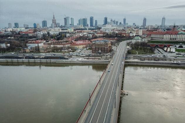 (200321) -- WARSAW, March 21, 2020 (Xinhua) -- Aerial photo taken on March 20, 2020 shows vehicles crossing the Vistula river on a bridge in Warsaw, Poland. Polish Prime Minister Mateusz Morawiecki said on Friday that Poland has introduced a state of epidemic emergency to curb the spread of the novel coronavirus. The prime minister also announced the introduction of tougher penalties for breaking quarantine rules and affecting location-tracking of people under quarantine. The number of Poland s confirmed coronavirus cases has risen to 425 and five people died from the COVID-19, the Polish Health Ministry announced on Friday evening. (Xinhua Zhou Nan) POLAND-WARSAW-COVID-19 
