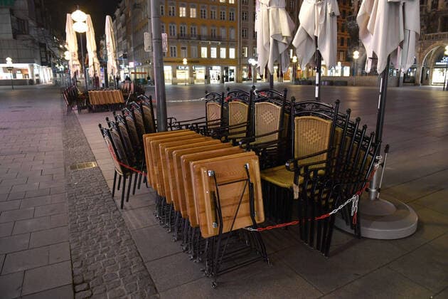 Theme picture Corona pandemic Bavaria decides to restrict the exit from the empty Marienplatz, pedestrian zone in Munich on the late evening before the curfew is imposed on 20 03 2020 Tables and chairs of the restaurants and bars are folded and chained up Some people are still on the move