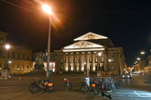 Theme picture Corona pandemic Bavaria decides to limit the exit Max Joseph Platz with a view of the National Theatre, Opera n Munich on the late evening before the curfew is imposed on 20 03 2020 Pedestrians, people on the move, with detached rental bikes in the foreground, are still sporadically