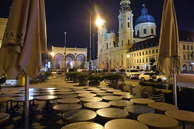 Theme picture Corona pandemic Bavaria decides to restrict the exit View of the Odeonsplatz with the Feldherrnhalle and the Theatinerkirche in Munich In the foreground are the bistro tables of the Cafe Tambosi chained together on the late evening before the restriction of the exit on 20 03 2020 A few taxis are standing at the roadside