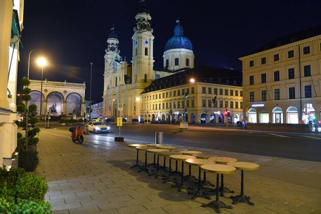 Theme picture Corona pandemic Bavaria decides to restrict the exit View of the Odeonsplatz with the Feldherrnhalle and the Theatinerkirche in Munich In the foreground are the bistro tables of the Cafe Tambosi chained together on the late evening before the restriction of the exit on 20 03 2020 A few taxis are standing at the roadside