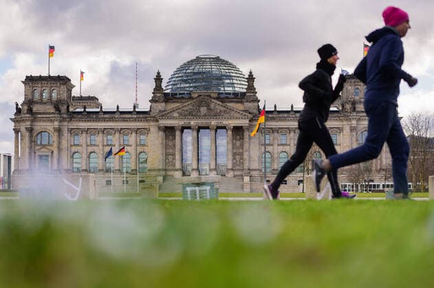 March 21, 2020: Two joggers pass the empty Platz der Republik in front of the German Reichstag. The Governing Mayor of Berlin, Michael Mueller (SPD), prepares restricting residents movements to contain the deadly coronavirus pandemic. Public venues such as bars, clubs, museums, cinemas, schools, daycare centers and universities have already closed. Many businesses are resorting to home office work for their employees. And travel across the border to most neighbouring countries is severely restricted. - ZUMAs172 20200321_zap_s172_007 Copyright: xJanxScheunertx