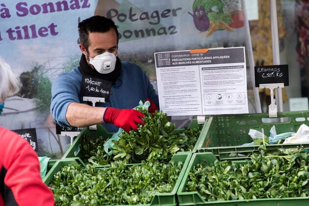 Chambery, France March 21, 2020 - Morning atmosphere at the downtown market during the period of confinement due to the coronavirus health crisis - A saleswoman wearing a sanitary mask serves vegetables to customers EPIDEMIE, CORONAVIRUS, VIRUS, CRISE SANITAIRE, COVID19, VIE QUOTIDIENNE, MARCHE, ALIMENTAIRE, COMMERCANTS, RESTRICTIONS, PANDEMIE, SANTE, AMBIANCE, ATMOSPHERE, CONFINEMENT, INQUIETUDES, FAIRE DES COURSES, RESTRICTIONS DE CIRCULATION, APPROVISIONNEMENT, PRODUITS DE PREMIERE NECESSITE, MALADIE, CHAMBERY, SAVOIE, PROPAGATION DU VIRUS, ALIMENTATION, MASQUE SANITAIRE, LEGUMES Copyright: xVincentxIsorex