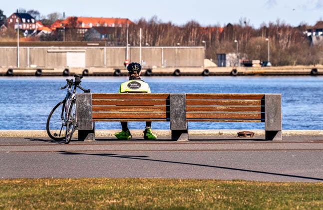A cyclist relaxes alone on a bench at the waterfront in Aalborg, Saturday March 21, 2020 Along the entire harbor in Aalborg, there was a good distance between the many people who were out and enjoying the weather Because of COVID 19, the people were asked as far as possible to stay indoors and outdoors in the great spring weather must take place at a good distance, Aalborg Jylland Denmark,  Copyright: HenningxBagger HenningxBaggerx COP110 spdk20200321-131500-L