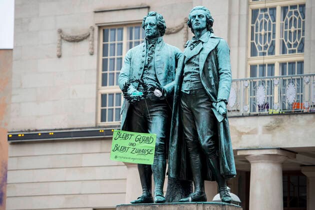 COVID 19 LIFE IN WEIMAR 20 03 2020 Weimar The Goethe Schiller Monument on the Theaterplatz in Weimar on 20 March 2020 The statues have a sign saying Stay healthy and stay at home and mouthguards in their hands