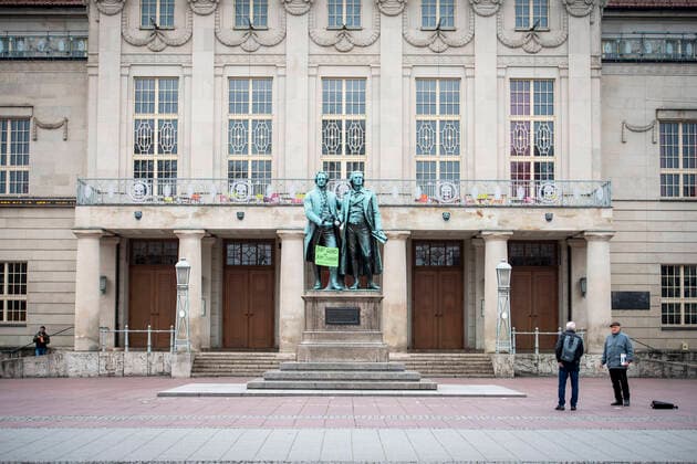 COVID 19 LIFE IN WEIMAR 20 03 2020 Weimar The Goethe Schiller Monument on the Theaterplatz in Weimar on 20 March 2020 The statues have a sign saying Stay healthy and stay at home and mouthguards in their hands