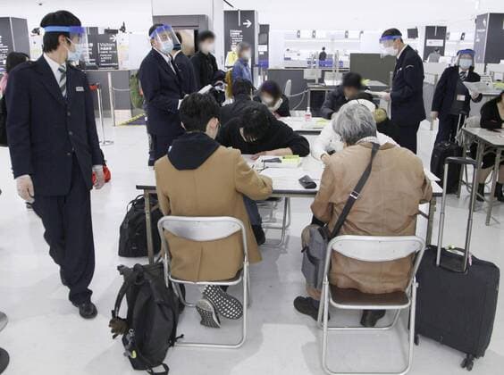 Two-week quarantine in Japan for travelers from Europe Arriving passengers (in seats) fill out forms as quarantine officials watch at Narita airport near Tokyo on March 21, 2020. Travelers from Europe, Egypt and Iran are required to self-quarantine for 14 days after their arrival as Japan attempts to contain the spread of the new coronavirus. 
