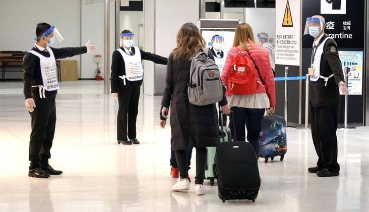 Two-week quarantine in Japan for travelers from Europe Quarantine officials wearing face shields direct arriving passengers at Narita airport near Tokyo on March 21, 2020. Travelers from Europe, Egypt and Iran are required to self-quarantine for 14 days after their arrival as Japan attempts to contain the spread of the new coronavirus. 