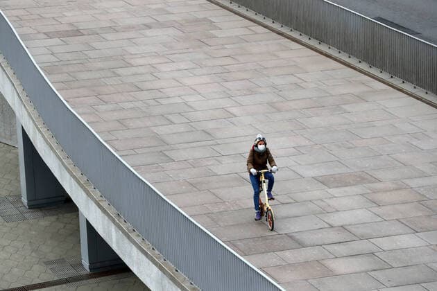 MOSCOW, RUSSIA - MARCH 21, 2020: A young woman in a face mask ride a bicycle on Patriarshy Bridge in central Moscow. As of 21 March 2020, Russia has confirmed more than 250 cases of the novel coronavirus, with more than 130 cases in Moscow. Sergei Karpukhin TASS  TS0D3009