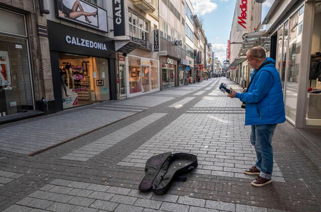 Effects of the coronavirus crisis, empty shopping street, lonely street musician, around 1400 on Saturday, usually thousands of people go shopping here at this time, Hohe Strasse in Cologne, Germany, Corona crisis