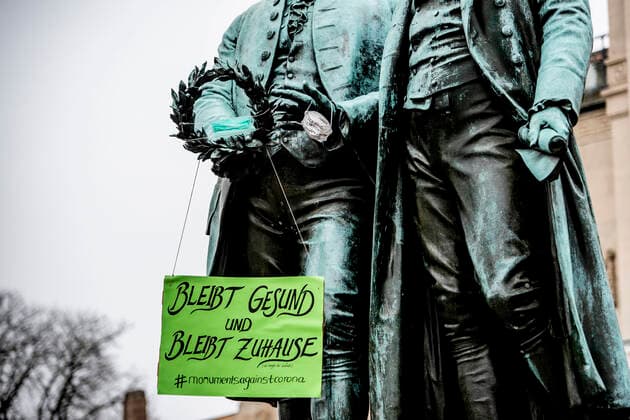 COVID 19 LIFE IN WEIMAR 20 03 2020 Weimar The Goethe Schiller Monument on the Theaterplatz in Weimar on 20 March 2020 The statues have a sign saying Stay healthy and stay at home and mouthguards in their hands