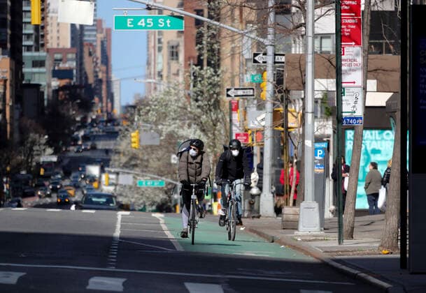 (200322) -- NEW YORK, March 22, 2020 -- People wearing face masks ride bikes on the 2nd Avenue in New York, the United States, March 21, 2020. Governor of the U.S. state of New York Andrew Cuomo said on Saturday that a total of 10,356 people in the state had tested positive for novel coronavirus, jumping 3,254 compared with the previous day. On Friday, Cuomo announced that a mandate, which requires people working in non-essential businesses to stay at home, will take effect Sunday night. ) U.S.-NEW YORK-COVID-19-MANDATE WangxYing