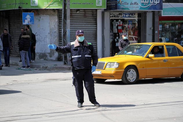 (200322) -- GAZA, March 22, 2020 -- A policeman wearing a mask directs the traffic at an intersection in Gaza City, March 22, 2020. Two Palestinians in Gaza have tested positive for COVID-19, becoming the first cases recorded in the Hamas-ruled enclave, a health official said early Sunday. A total of 53 Palestinians have been infected with the virus since March 5, and 17 of them have recovered, the health ministry in the West Bank said earlier Saturday. (Photo by Rizek Abdeljawad Xinhua) MIDEAST-GAZA-COVID-19 xiongsihao 
