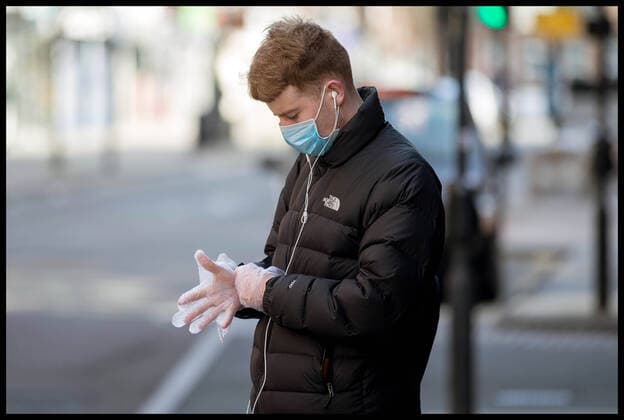 . 22 03 2020. London, United Kingdom. Ongoing Coronavirus Crisis. A man wearing a surgical mask puts on a pair of plastic gloves during Coronavirus crisis.  xMartynxWheatleyx xi-Imagesx IIM-20944-0016