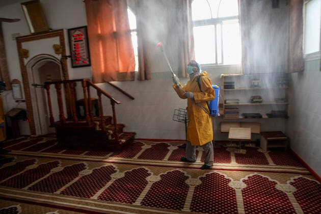Palestinian volunteers wearing protective clothes and masks disinfect the interior of a mosque as a preventive measure against the spread of novel coronavirus, in Rafah in the southern Gaza Strip, on Sunday, March 22, 2020. Authorities in Gaza today confirmed the first two cases of novel coronavirus, identifying them as Palestinians who had traveled to Pakistan and were being held in quarantine since their return. The United Nations has warned that a COVID-19 outbreak in Gaza could be disastrous, given the high poverty rates and weak health system in the coastal strip under Israeli blockade since 2007.  GAZ2020032201 ISMAELxMOHAMAD