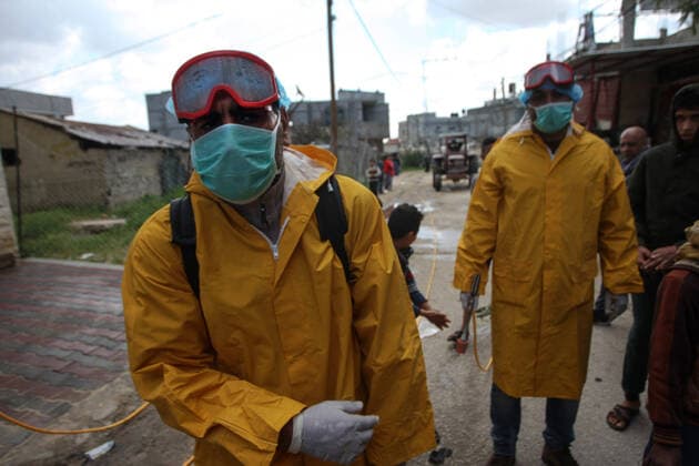 Palestinian volunteers wearing protective clothes and masks disinfect a street as a preventive measure against the spread of novel coronavirus, in Rafah in the southern Gaza Strip, on Sunday, March 22, 2020. Authorities in Gaza today confirmed the first two cases of novel coronavirus, identifying them as Palestinians who had traveled to Pakistan and were being held in quarantine since their return. The United Nations has warned that a COVID-19 outbreak in Gaza could be disastrous, given the high poverty rates and weak health system in the coastal strip under Israeli blockade since 2007.  GAZ2020032205 ISMAELxMOHAMAD
