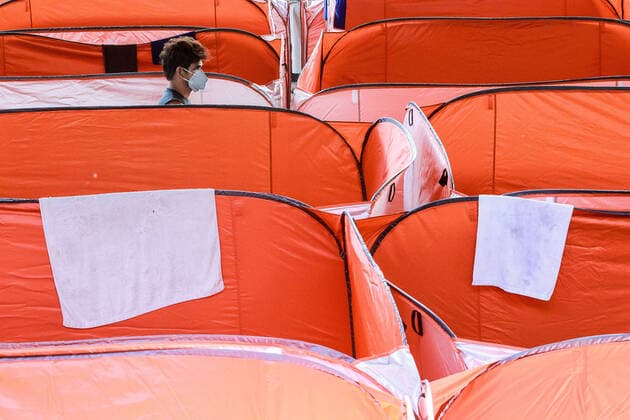 (200323) -- MANILA, March 23, 2020 -- A man wearing a face mask walks between modular tents set up for street dwellers to stop the further spread of COVID-19 at a sheltered basketball court in Manila, the Philippines on March 23, 2020. The Philippine health authorities confirmed on Sunday 73 new cases of COVID-19 in the country, bringing the total number of people sick with the highly contagious disease to 380. ) PHILIPPINES-MANILA-COVID-19-MODULAR TENTS ROUELLExUMALI 