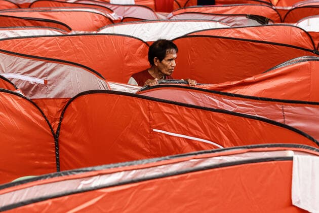 (200323) -- MANILA, March 23, 2020 -- A man stands in a modular tent set up for street dwellers to stop the further spread of COVID-19 at a sheltered basketball court in Manila, the Philippines on March 23, 2020. The Philippine health authorities confirmed on Sunday 73 new cases of COVID-19 in the country, bringing the total number of people sick with the highly contagious disease to 380. ) PHILIPPINES-MANILA-COVID-19-MODULAR TENTS ROUELLExUMALI 