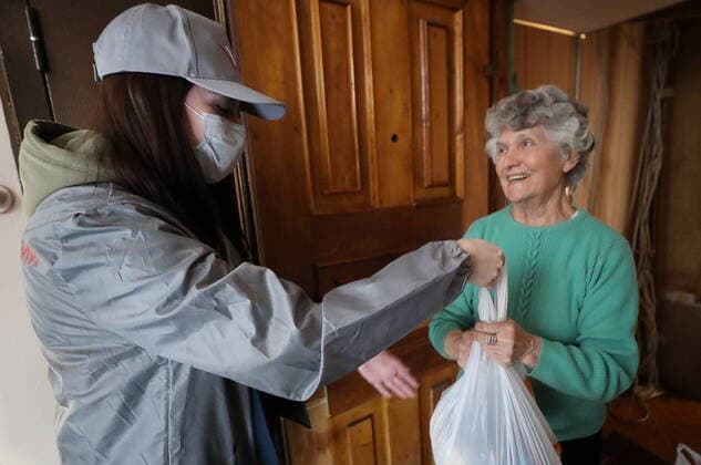 ST PETERSBURG, RUSSIA - MARCH 23, 2020: A medical volunteer delivering groceries to an elderly woman in quarantine amid the COVID-19 coronavirus pandemic. Medical volunteers and the Russian Popular Front are opening volunteer centers to help the elderly who are at higher risk of COVID-19 and are staying at home to avoid the coronavirus infection. Alexander Demianchuk TASS  TS0D3247