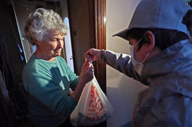 ST PETERSBURG, RUSSIA - MARCH 23, 2020: A medical volunteer delivering groceries to an elderly woman in quarantine amid the COVID-19 coronavirus pandemic. Medical volunteers and the Russian Popular Front are opening volunteer centers to help the elderly who are at higher risk of COVID-19 and are staying at home to avoid the coronavirus infection. Alexander Demianchuk TASS  TS0D324A