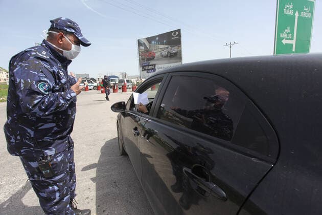 (200323) -- NABLUS, March 23, 2020 -- A Palestinian policeman speaks to a driver at a checkpoint at the entrance of the West Bank city of Nablus, March 23, 2020. Palestinian authorities on Sunday declared a 14-day lockdown on the West Bank as part of measures to combat the spread of coronavirus pandemic. Prime Minister Mohammed Ishtaye announced a ban on transportation and movement between the West Bank districts, urging citizens to stay at home. (Photo by Nidal Eshtayeh Xinhua) MIDEAST-NABLUS-COVID-19-MEASURES XiongxSihao 