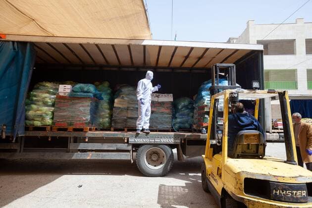 (200323) -- BETHLEHEM, March 23, 2020 -- A Palestinian worker wearing protective gear unloads fruits and vegetables donated by farmers from the Jordan Valley to families in the West Bank city of Bethlehem on March 23, 2020. Palestinian authorities on Sunday declared a 14-day lockdown on the West Bank as part of measures to combat the spread of coronavirus pandemic. Prime Minister Mohammed Ishtaye announced a ban on transportation and movement between the West Bank districts, urging citizens to stay at home. (Photo by Luay Sababa Xinhua) MIDEAST-BETHLEHEM-COVID-19-MEASURES XiongxSihao 