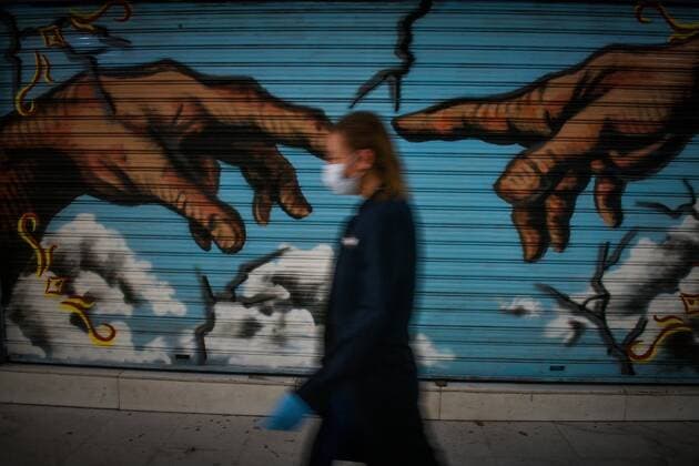 March 23, 2020, Athens, Greece: Woman with face mask walk next to graffiti in the center of Athens Athens Greece - ZUMAe114 20200323_zaa_e114_009 Copyright: xEurokinissix