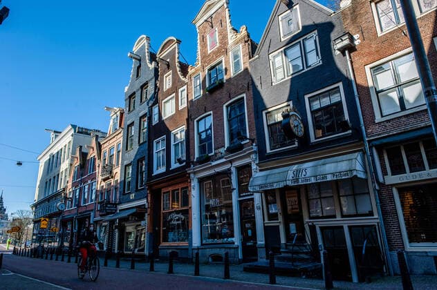 March 23, 2020, Amsterdam, Netherlands: A woman rides a bike through an empty street..Since the Coronavirus hit The Netherlands, most of the cities are empty. A couple of weeks ago, Prime Minister Mark Rutte called to work from home as much as possible and also announced the closure of restaurants, sports clubs, sex clubs, saunas, and cafes. Amsterdam is not formally in lockdown, but the streets and squares are empty. Amsterdam Netherlands - ZUMAs197 20200323_zaa_s197_059 Copyright: xAnaxFernandezx