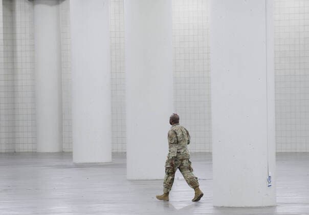 A National Guard man in uniform walks through an empty section of Jacob Javits Convention Center before Gov. Andrew Cuomo speaks with the National Guard on site in New York City on Monday, March 23, 2020. The Javits Center is setting up to be turned into field hospitals to test and possibly treat cases of COVID-19 infections. New York state now accounts for about 1 percent of the coronavirus-related deaths in the world and New York City has more than 12,300 of those cases.  NYP20200323117 JOHNxANGELILLO