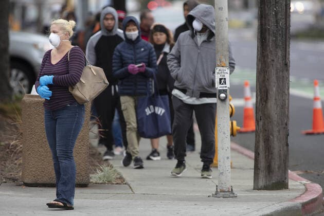 Members of the public practice social distancing while waiting in line to be checked by Hayward emergency-medical technician for symptoms and high temperature at a triage station for Coronavirus in Hayward, California on Monday, March 23, 2020. If the individual has symptoms, they are directed to be tested for CIVID-19 at a separate testing tent.  SFP2020032340 PETERxDASILVA