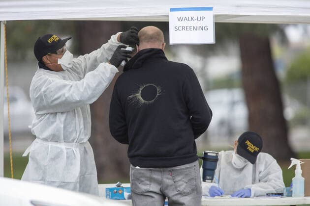 An individuals has his temperature checked by a Hayward emergency-medical technician for symptoms and high temperature at a triage station for Coronavirus in Hayward, California on Monday, March 23, 2020. If the individual has symptoms, they are directed to be tested for CIVID-19 at a separate testing tent.  SFP2020032343 PETERxDASILVA