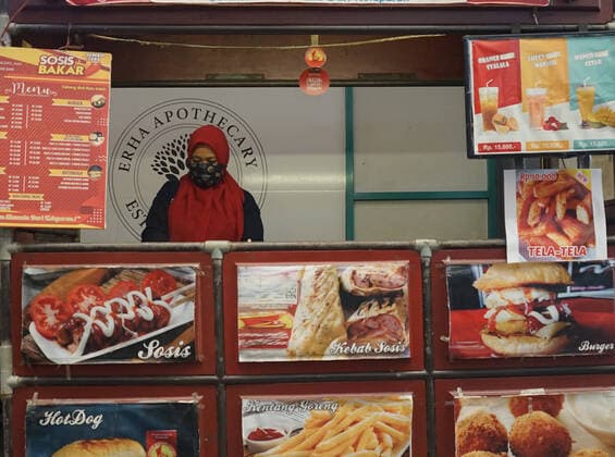 March 24, 2020, Makassar, South Sulawesi, Indonesia: A food seller wears a mask while waiting for his customers in Mall Ratu Indah, Makassar City, South Sulawesi Province, Indonesia. This food seller woman wearing a mask to protect themselves from the spread of coronavirus. Makassar Indonesia - ZUMAb223 20200324_zip_b223_017 Copyright: xHerwinxBaharx