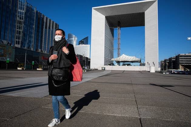 Puteaux, France, March 24, 2020 - Atmosphere in the business district of La Defense after the head of state ordered people to stay home to stop the spread of Covid-19 - A woman wearing a mask walks on the esplanade of La Defense, leaving the Grande Arche behind.  Copyright: xAlexisxSciardx