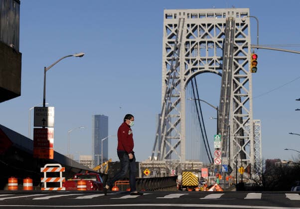 A pedestrian wearing a protective mask crosses a Manhattan street near the George Washington Bridge in New York City on Tuesday, March 24, 2020. New York state reports the most coronavirus cases and deaths in the country with more than 23,230 confirmed cases and 188 deaths.  NYP20200324110 JOHNxANGELILLO