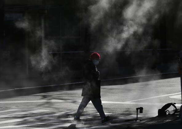 A pedestrian crosses the street wearing a protective mask near Lincoln Center in New York City on Tuesday, March 24, 2020. New York state reports the most coronavirus cases and deaths in the country with more than 23,230 confirmed cases and 188 deaths.  NYP20200324124 JOHNxANGELILLO