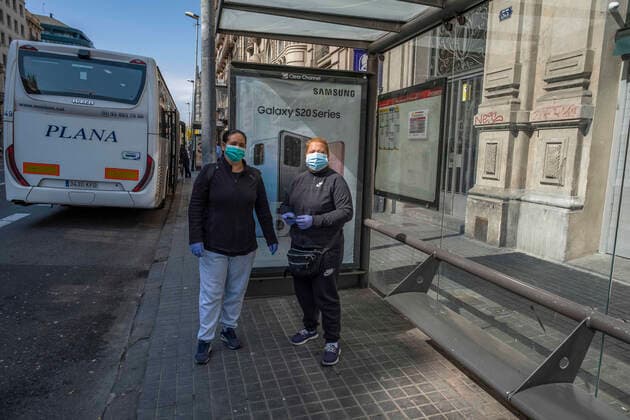 March 24, 2020, Barcelona, Catalonia, Spain: Two cleaning workers are seen waiting for the bus wearing sanitary masks as a preventive measure, during the period of confinement..Barcelona faces its tenth day of confinement decreed by the Government of Spain due to the spread of the coronavirus. Barcelona Spain - ZUMAs197 20200324_zaa_s197_128 Copyright: xPacoxFreirex