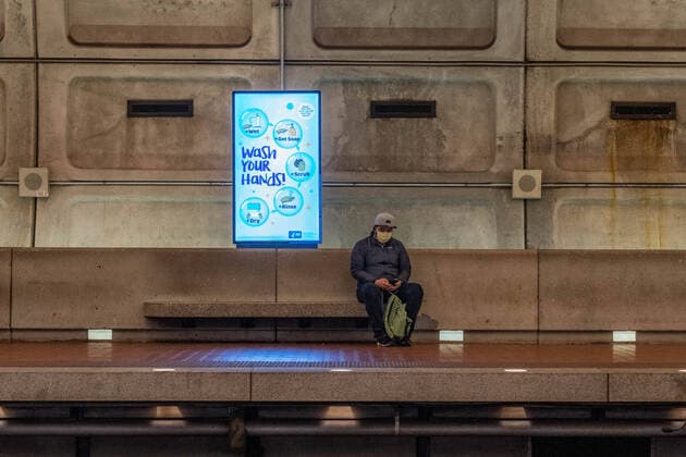March 24, 2020, Bethesda, MD, UNITED STATES: A man sits at a local metro station next to a sign that reads Ã Wash Your Hands, in mid day in Washington, DC on Tuesday, March 24, 2020. To date the United States has 52,966 Corona Virus cases and 685 deaths. President Donald Trump says he wants the nation opened up and just raring to go by Easter -- a date just more than two weeks away that few health experts believe will be sufficient in containing the spread of coronavirus. Bethesda UNITED STATES - ZUMAc206 20200324_zap_c206_012 Copyright: xKenxCedenox