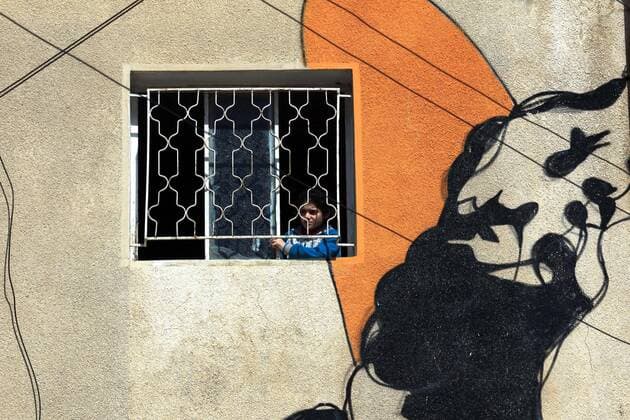 (200324) -- AMMAN, March 24, 2020 -- A child looks out from a window in Amman, Jordan, on March 24, 2020. Jordan on Tuesday started allowing the distribution of bread, bottled water and medicine across the country, an official said on Tuesday. The number of COVID-19 cases reached 153 in the country on Tuesday. (Photo by Xinhua) JORDAN-AMMAN-COVID-19 MohammadxAbuxGhosh 