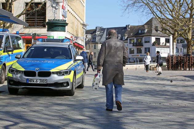 Coronavirus anxiety, effects due to coronavirus Covid 19 , the city center of Siegen is almost empty at noon, police car in the city center, a man walks by with a pack of toilet paper downtown on 25 03 2020 in Siegen Germany