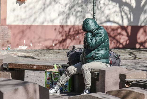 A homeless person sits muffled up in the warming sun on the deserted town hall place in Freiburg In times of Corona the starting possibilities and offers of help for homeless people worsen dramatically warming rooms, boards for instance have closed photo Winfried Rothermel