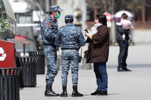 YEREVAN, ARMENIA - MARCH 25, 2020: Police officers in face masks talk to a woman in a street during the pandemic of the novel coronavirus (COVID-19). As of 25 March 2020, Armenia has confirmed more than 250 cases of the novel coronavirus. The Armenian government declared a state of emergency and enforced restricted movement in connection with the pandemic on 16 March. Hayk Baghdasaryan Photolure TASS  TS0D354A