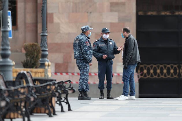 YEREVAN, ARMENIA - MARCH 25, 2020: Police officers in face masks talk to a man in a street during the pandemic of the novel coronavirus (COVID-19). As of 25 March 2020, Armenia has confirmed more than 250 cases of the novel coronavirus. The Armenian government declared a state of emergency and enforced restricted movement in connection with the pandemic on 16 March. Hayk Baghdasaryan Photolure TASS  TS0D354B