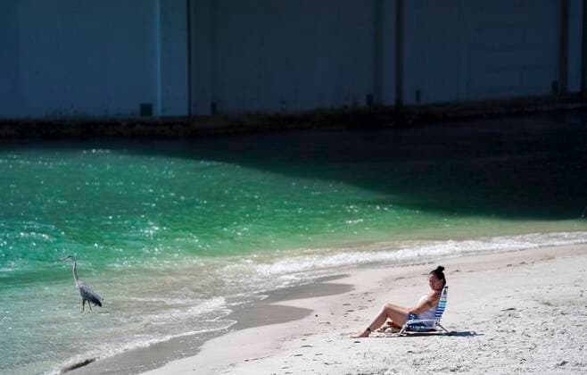 March 25, 2020, Madeira Beach, Florida, USA: A woman sunbathes while a heron wades in the water at John s Pass on Wednesday, March 25, 2020 in Madeira Beach. Madeira Beach USA - ZUMAs70_ 20200325_zan_s70_099 Copyright: xMarthaxAsencioxRhinex