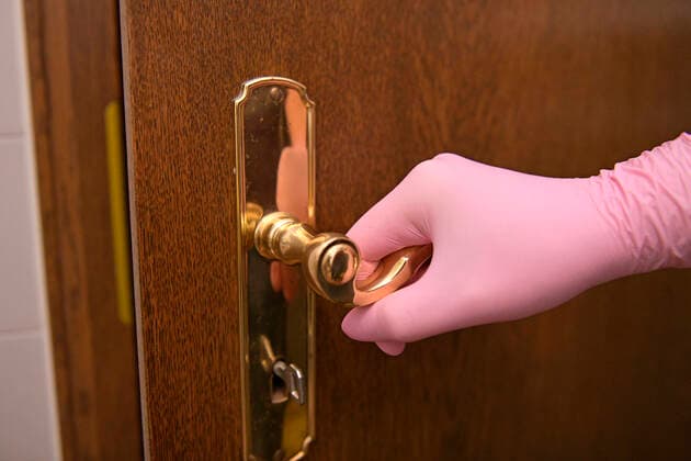 26 03 2020, Woman presses a door handle with rubber gloves to protect against bacteria and viruses 26 03 2020, infection protection 26 03 2020, infection protection