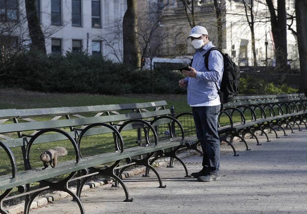A man wearing a protective face mask feeds squirrels surrounded by empty benches in an uncrowded Central Park in New York City on Thursday, March 26, 2020. The U.S. Now Leads the World in Confirmed Coronavirus Cases.  NYP20200326122 JOHNxANGELILLO