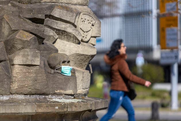 Stuttgart, 27.03.2020: Makabrer Scherz: Ein Totenkopf mit Atemschutzmaske. Kreuzigungsgruppe von Hans Seyfer an der Leonhardskirche Stuttgart. DEU, Deutschland, Baden-Württemberg