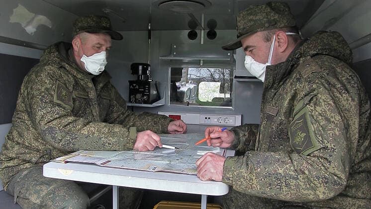 BERGAMO, ITALY - MARCH 27, 2020: Pictured in this video grab are Russian military officers in respirators looking at a map at an Italian Air Force base, on the outskirts of Bergamo in Alpine Lombardy, one of the worst hit regions of Italy during the pandemic of the novel coronavirus (COVID-19). Russia has sent more than 100 military virologists, epidemiologists and CBRN specialists to Italy to help battle the pandemic. Russian military specialists are involved in sanitising and disinfecting healthcare facilities, urban infrastructure, and vehicles. Video grab. Defence Ministry of the Russian Federation TASS  TS0D38D4